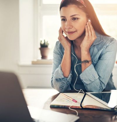 employee-woman-with-headphones-looking-at-laptop-VUA7MQH